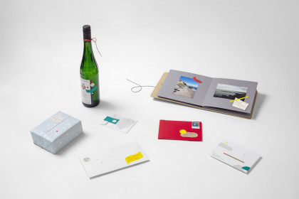vyplněné fotoalbum, zelená lahev od vína, dopis a dárek ležící na stole
